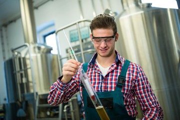 Een man die een maatglas en hydrometer vasthoud om de SG-waarde (soortelijk gewicht) van bier te meten